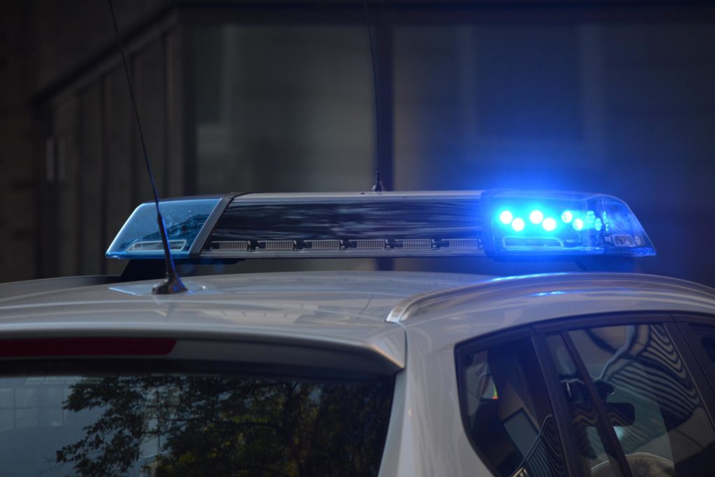 An image of the top of a police car, with blue siren lights on.